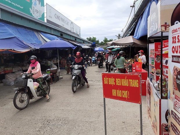 Người dân chấp hành tốt việc đeo khẩu trang trước khi vào chợ Phù Cát  (Ảnh. Thế Hà)